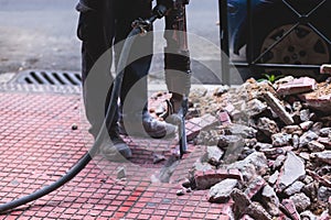 Process of sidewalk road repairing with jackhammer, builder worker with pneumatic hammer and drill equipment breaking asphalt