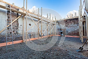 Process of solidification of concrete floor before pouring and reinforcement of load-bearing walls with wooden beams photo