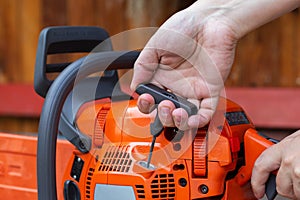 The process of starting a chainsaw. A male worker pulls the starting cable of a chainsaw with his hand. Close-up