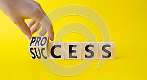 Process and Success symbol. Businessman Hand turns a cube and changes the word success to process. Beautiful yellow background.