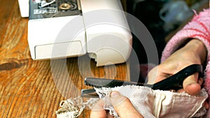 Process of tailoring working, hands of elderly seamstress cut the fabric.