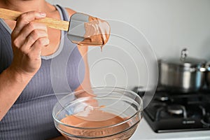 The process of tempering chocolate and making chocolates. Pastry chef using spatula tempering molten chocolate