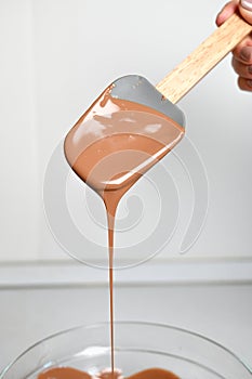 The process of tempering chocolate and making chocolates. Pastry chef using spatula tempering molten chocolate. Vertical