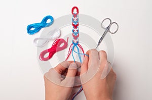 Process of weaving knot for DIY friendship bracelet. Female hands. step by step. White background with copy space