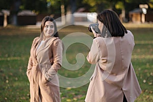 Process of woman photographer make a photo for gorgeous female in park