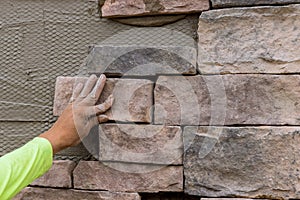 The process of worker laying decorative bricks stone on the wall.