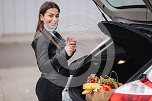 A process of young attractive woman taking groceries from a supermarket from the trolley to car truck. Social distancing