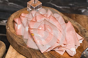 Processed cold meat products, on a wooden cutting board.