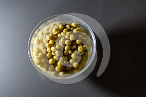 Processed pea grains in a glass bowl on an opaque background