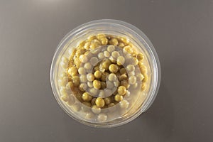 Processed pea grains in a glass bowl on an opaque background