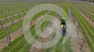 Processing of an apple orchard. A green tractor in an apple orchard. Spraying the garden with a tractor. Tractor sprays