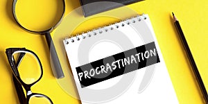 Procrastination. Motivation. Concept meaning delay or put off something boring written on a notepad on a yellow desk. View from