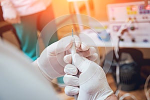 Proctologist holding an anoscope against a proctological chair.