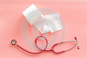Proctology concept with toilet paper roll and stethoscope on pink background top view