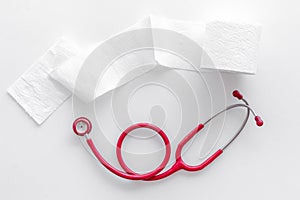 Proctology concept with toilet paper roll and stethoscope on white background top view