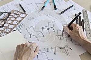 Product designer sketching concepts for a chair with pens and drawing instruments