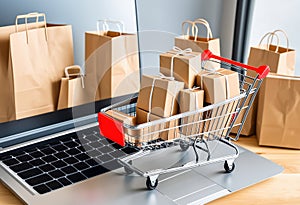 Product package boxes in cart next to computer with shopping bags on background. Web store for online shopping and delivery