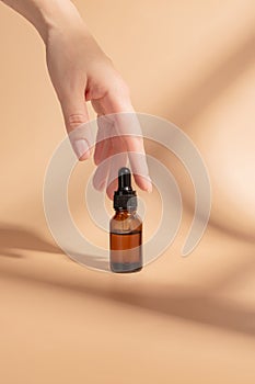 product package with serum and a woman hand in studio on a beige background to promote an antiaging treatment. Skincare