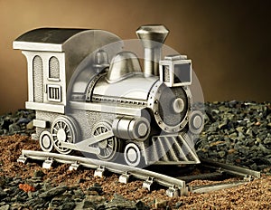 A Product Studio Shot of a Model Steam Engine Train with Track: The train is made of pewter and is also a coin bank.