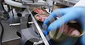 Production of canned meat. Finished cans of meat without labels are moved along the conveyor