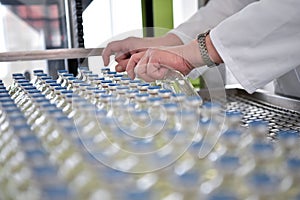 production and filling of drugs in a pharmaceutical conveyor belt with bottles and a worker