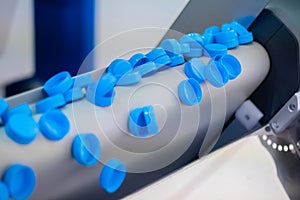 Production line - many blue plastic bottle caps falling from conveyor belt