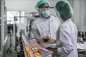 Production line supervisor and worker work together in beverage production line