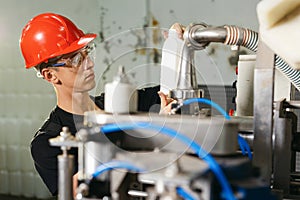 Production line worker or technologist in uniform working in chemical industry and checking quality of liquid soap