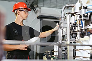 Production line worker or technologist in uniform working in chemical industry and checking quality of liquid soap