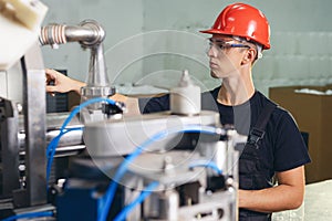 Production line worker or technologist in uniform working in chemical industry and checking quality of liquid soap