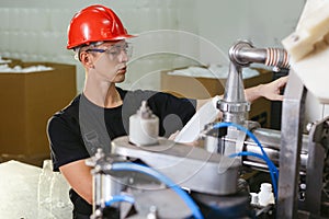 Production line worker or technologist in uniform working in chemical industry and checking quality of liquid soap