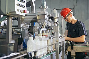 Production line worker or technologist in uniform working in chemical industry and checking quality of liquid soap