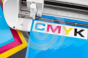 Production making CMYK sticker with plotter cutting machine on cyan blue colored vinyl film. Advertising Industry diy design