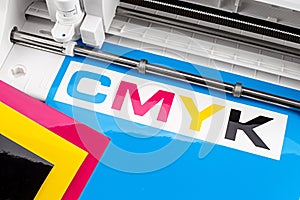 Production making CMYK sticker with plotter cutting machine on cyan blue colored vinyl film. Advertising Industry diy design