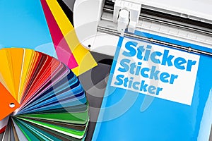 Production making sticker with plotter cutting machine CMYK cyan blue colored vinyl fim with color fan. guide. Advertising