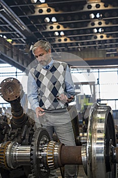 Production Manager With Digital Tablet Standing Next To Train Wheels At Train Factory