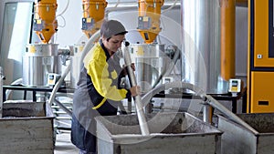 Production plant worker Works with loader Hose vacuum sucking white virgin plastic granules from tank in factory