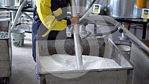 Production plant worker Works with loader Hose vacuum sucking white virgin plastic granules from tank in factory