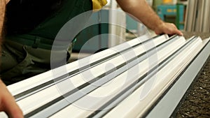 Production of pvc windows, male worker punctures the details of a pvc profile window, close-up, detail window