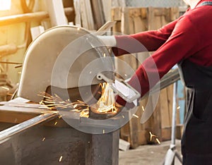 Production of pvc windows, worker cuts a metal profile on a circular saw, close-up, hand, sun