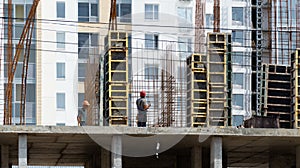 Production of structures made of rebar and concrete during the construction of a new house with silhouettes of workers.