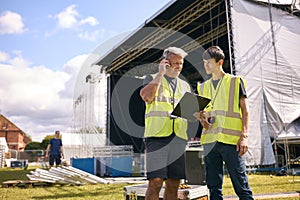 Production Team Talking On Radios And Setting Up Outdoor Stage For Music Concert Or Festival 