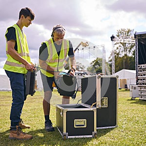 Production Team Unpacking Lights From Flight Case And Setting Up Outdoor Stage For Music Festival 