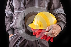 A production worker in workwear with a protective helmet in his hand. Special workwear for employees