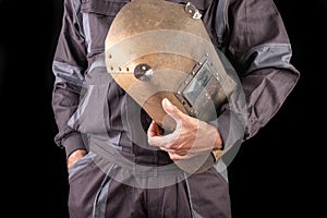 A production worker in workwear with a welding mask in hand. Special workwear for employees