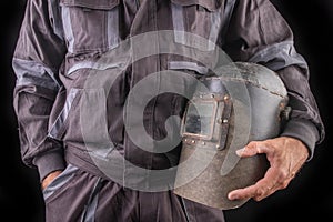 A production worker in workwear with a welding mask in hand. Special workwear for employees