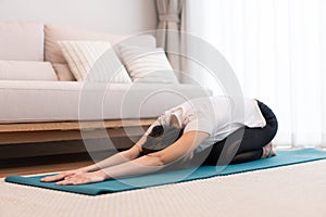 Productive activity concept in the living room a girl bending the body parallel to the floor on the green yoga mat willingly