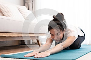 Productive activity concept in the living room a girl bending the body parallel to the floor on the green yoga mat willingly