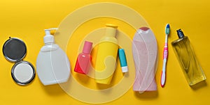 Products for beauty, self-care and hygiene on a yellow pastel background. Shampoo, perfume, lipstick, shower gel, toothbrush.