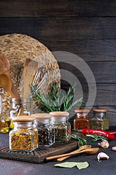 Products for cooking in kitchen, kitchen utensils, herbs, colorful dry spices in glass jars on dark